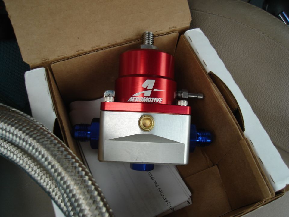 Aeromotive fuel pressure regulator in a cardboard box, with braided hose and car seat visible