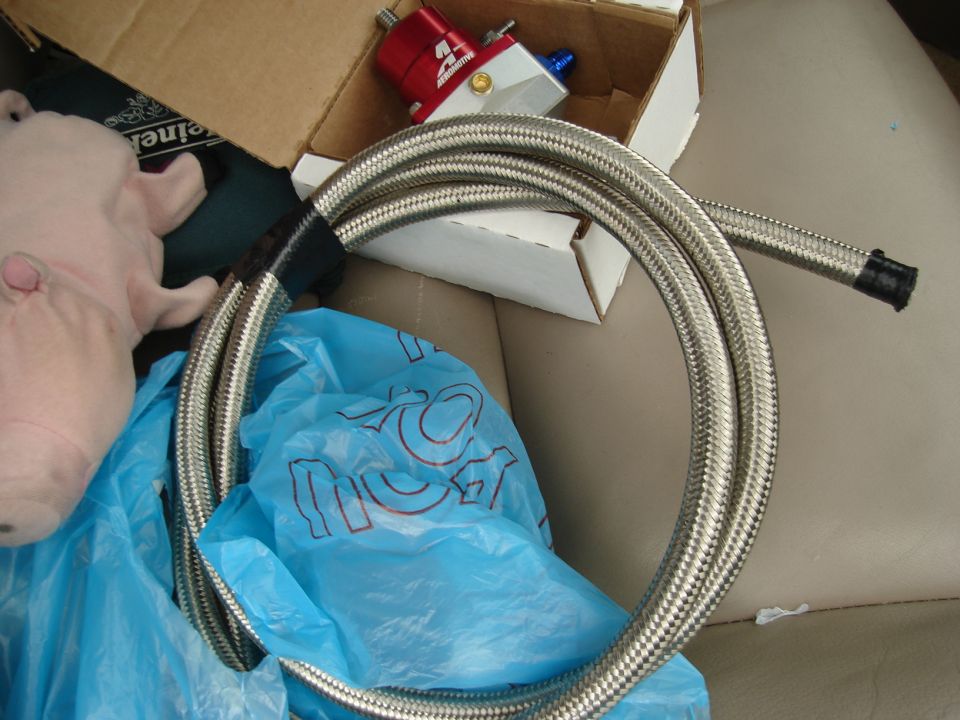 red fuel pressure regulator and braided hose in a car seat