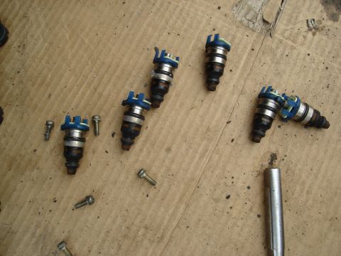 1995 Mazda MX-6 - These fuel injectors and screws appear to have been removed for maintenance or replacement.