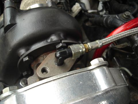 1995 Mazda MX-6 - Close-up of a turbocharger oil line fitting, part of a custom engine build.