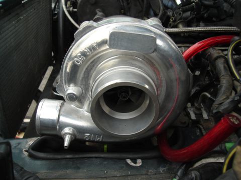 1995 Mazda MX-6 - Close-up of a turbocharger, identified with A/R 50 markings, installed in an engine bay.