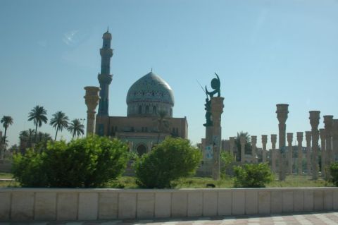 1996 Ford Bronco - A mosque complex a prominent dome and minaret, with decorative columns and palm trees under a clear sky.