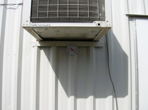 1996 Ford Bronco - An outdoor air conditioning unit is mounted on a white corrugated metal wall, with a thermometer showing the temperature.