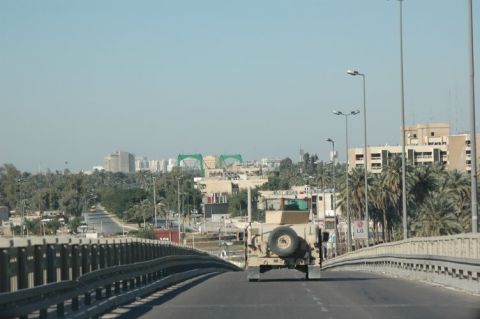 1996 Ford Bronco - A military vehicle travels across a bridge, with a city skyline visible in the distance.