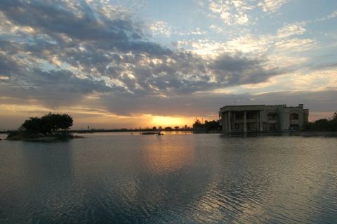 1996 Ford Bronco - A tranquil lake scene at sunset, with a large building and a small island visible.