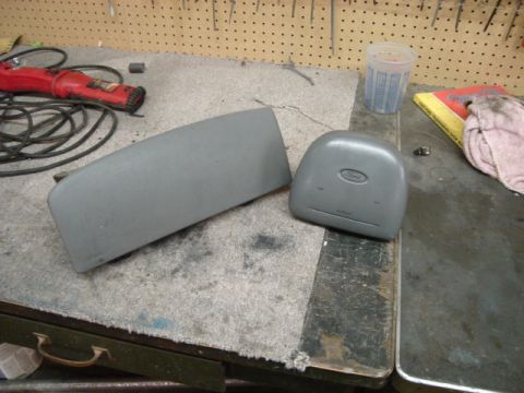 2000 Ford Crown Victoria - Two gray interior car parts, likely from a Ford, are laid out on a workbench.