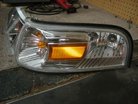 2000 Ford Crown Victoria - A single headlight assembly is shown, likely for a car, with visible internal components and an amber turn signal reflector.