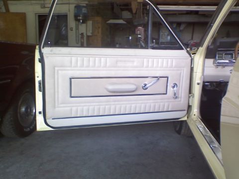 1967 Ford Ranchero - Interior door panel of a 1967 Ford Ranchero, showing beige upholstery and chrome accents.