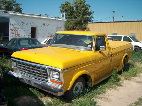 1979 Ford Bronco - A yellow 1979 Ford F-150 pickup truck is parked in a grassy lot next to other vehicles.