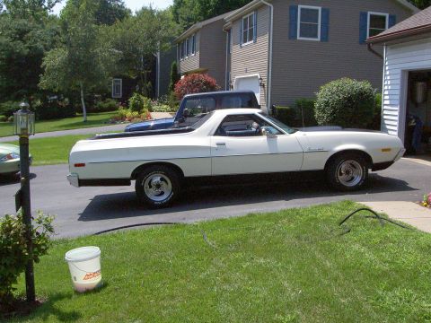 1972 Ford Ranchero - Passenger-side profile of a white Ford Ranchero coupe-utility parked in a driveway on a sunny day, showing its chrome-scripted front fender…
