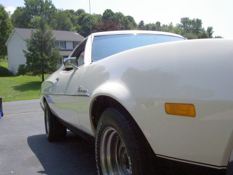1972 Ford Ranchero - A white 1972 Ford Ranchero is viewed from the front three-quarter angle, highlighting its chrome trim and amber marker light.