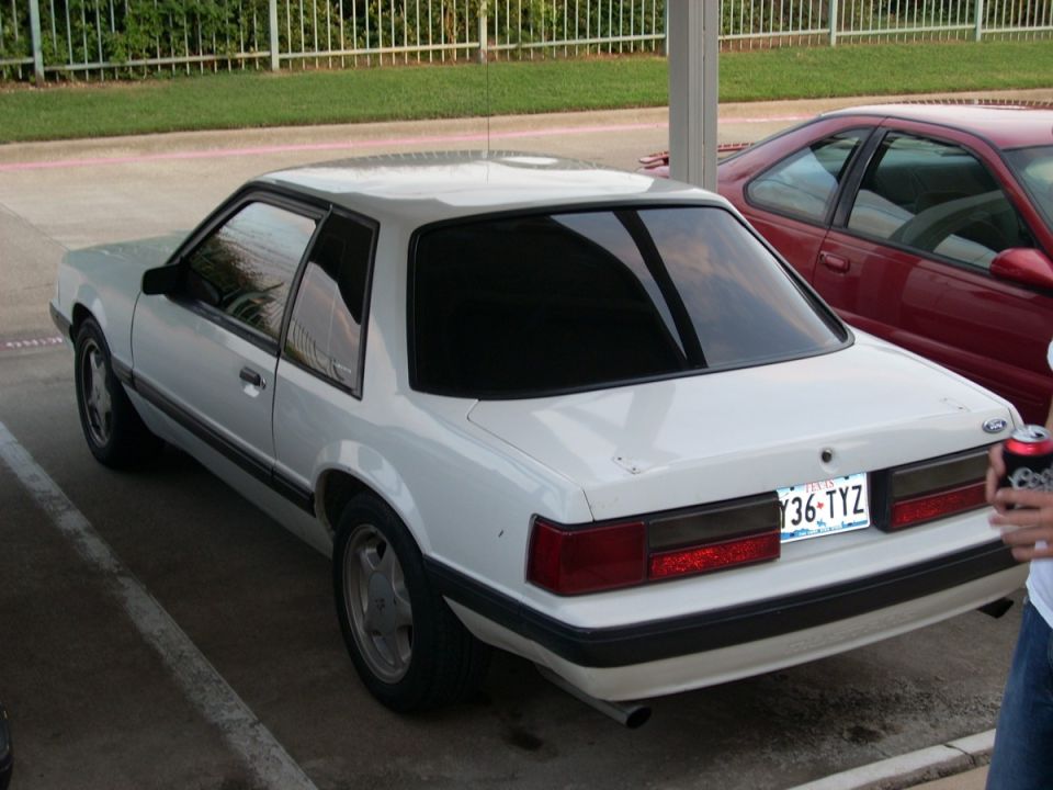 White 1991 Ford Mustang coupe parked next to a red car, rear view