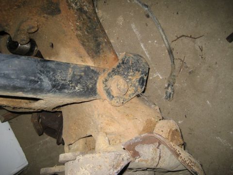 1995 Ford Bronco - The underside of a vehicle shows significant rust on its suspension components and frame.