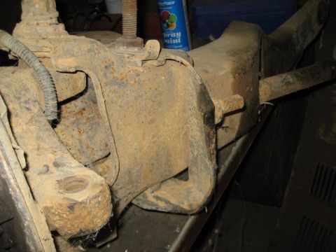 1995 Ford Bronco - Heavily rusted suspension part, likely from an older vehicle, in a workshop setting.