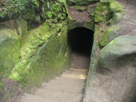 1991 Ford Probe - A moss-covered stone tunnel entrance with stairs descends into a dark opening, suggesting a hidden passage.