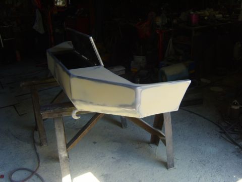 1989 Ford Bronco - A vehicle's front bumper is shown on sawhorses in a workshop, undergoing bodywork and preparation for repainting.