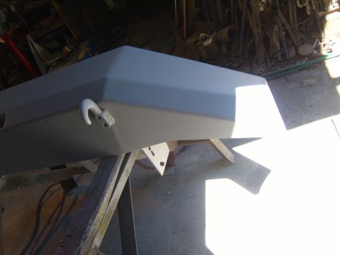 1989 Ford Bronco - A vehicle's front bumper, prepped for bodywork, rests on sawhorses in a workshop.