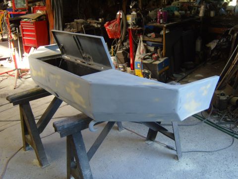 1989 Ford Bronco - A car bumper, prepped for bodywork, sits open on sawhorses in a cluttered garage.