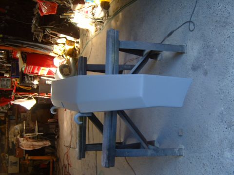 1989 Ford Bronco - A vehicle bumper is prepped for paint in a workshop setting.