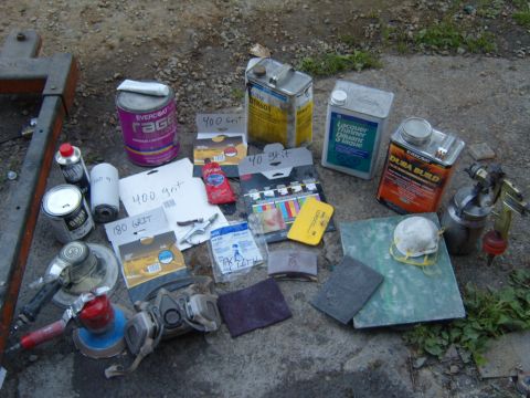 1989 Ford Bronco - A collection of automotive body repair supplies laid out on the ground, ready for use.