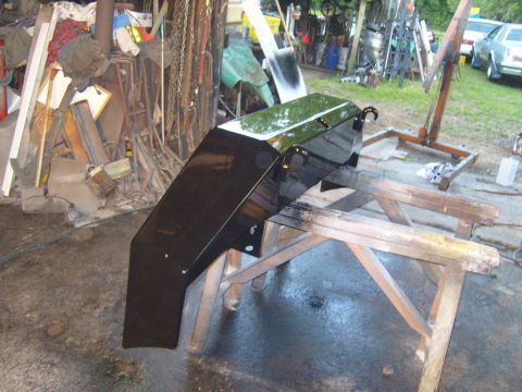 1989 Ford Bronco - A freshly painted black front bumper rests on sawhorses in a workshop setting.