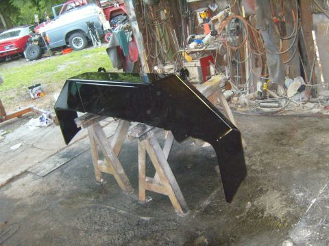 1989 Ford Bronco - Aftermarket bumper on sawhorses in a workshop setting with other vehicles present.