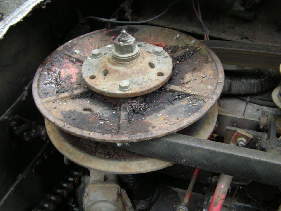 Close-up of a rusty pulley system with a chain drive, likely from a vehicle's mechanical components