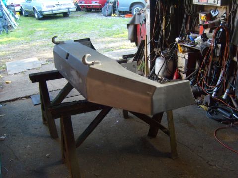 1989 Ford Bronco - Custom front bumper with tow hooks, undergoing bodywork in a workshop. Other vehicles are visible in the background.