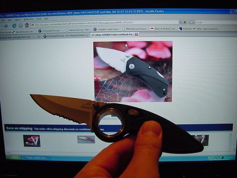 1989 BMW 3 Series - A hand holds a Gerber folding knife in front of a computer displaying an eBay listing for similar knives.