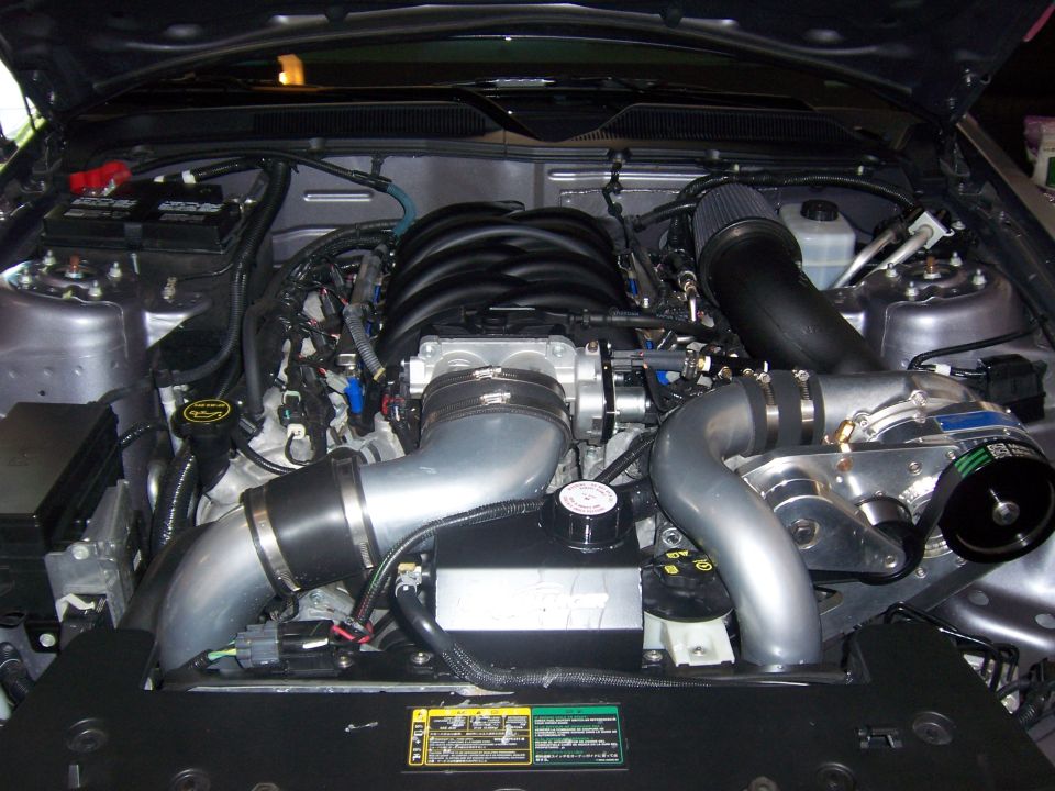 Engine bay with a supercharger, intake, and V8 engine components visible