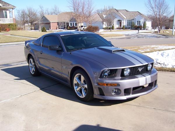 Gray Ford Mustang GT with silver racing stripes parked in a driveway