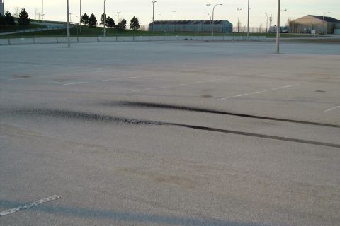 1977 Ford F-150 - Tire marks are visible on an empty asphalt lot under a cloudy sky.