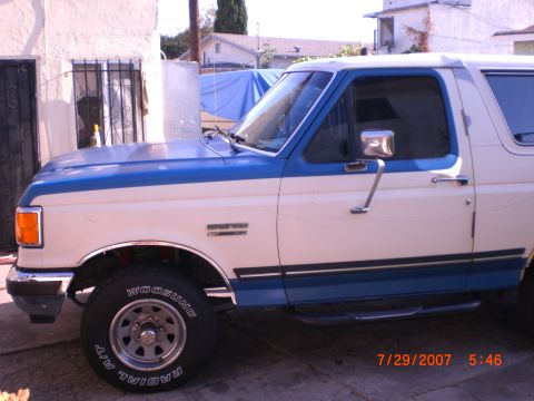 1991 Ford Bronco - Side view of a 1991 Ford Bronco with white and blue two-tone paint and chrome accents.