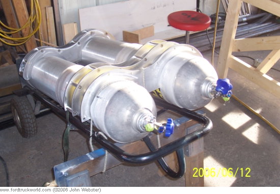 Dual aluminum fuel tanks on a metal cart with blue valves, seen from the side