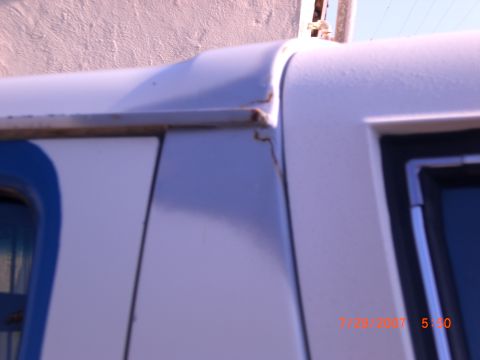 1991 Ford Bronco - Detail of a vehicle's body panel, showing rust near the roofline and a partial view of a window.