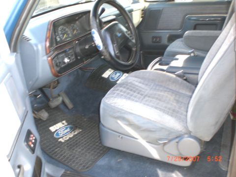 1991 Ford Bronco - The interior of a 1991 Ford Bronco features a blue dashboard, plaid seats, and Ford floor mats.
