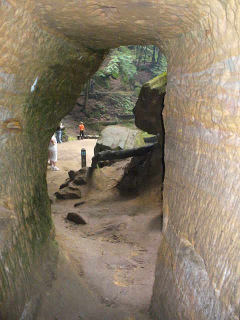1991 Ford Probe - People walk through a natural rock archway in a forest setting.