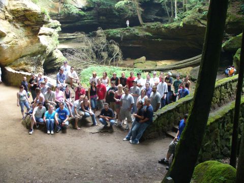 1991 Ford Probe - A large group of people pose for a photo in a picturesque natural gorge, surrounded by rock cliffs and lush greenery.