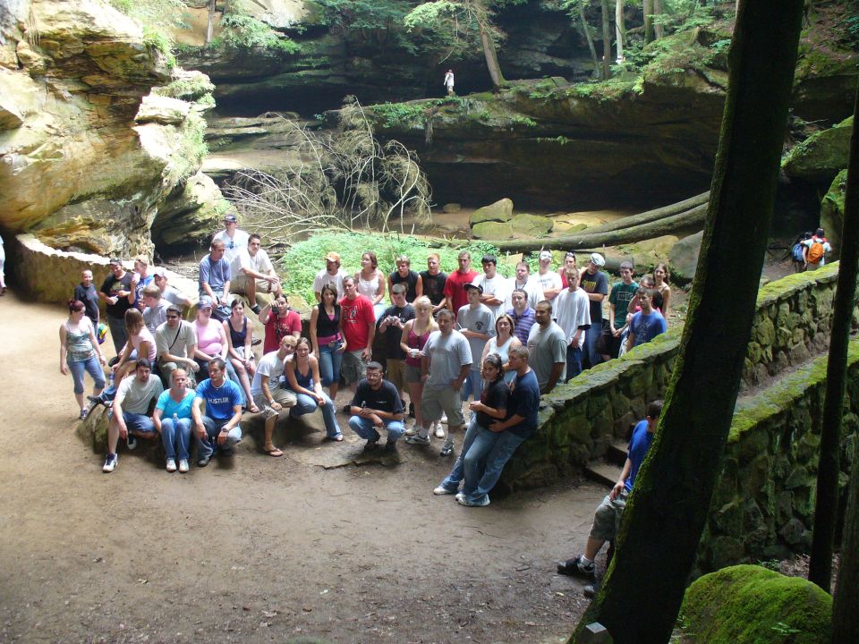 Group of people gathered in a scenic gorge with rock formations and trees