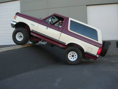 1991 Ford Bronco - 1991 Ford Bronco with lifted suspension is shown driving up an incline.