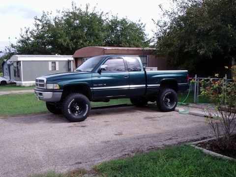 1996 Ford Bronco - This lifted green pickup truck features off-road tires and a prominent grille, suggesting a model from the mid-1990s.