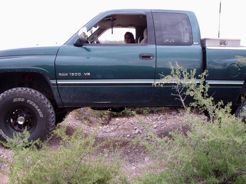 1996 Ford Bronco - A green Dodge Ram 1500 pickup truck is seen from the side, driving off-road.