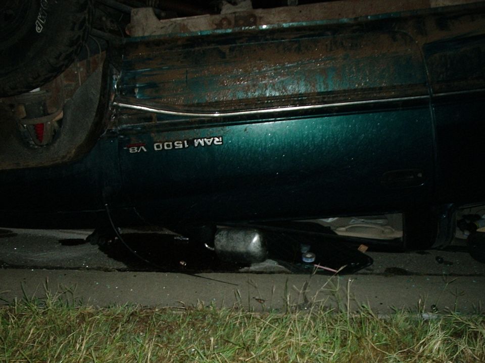 Side view of a green Dodge Ram 1500 V8, appears damaged and possibly overturned