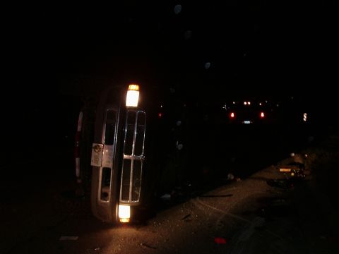 1996 Ford Bronco - Vehicle overturned on its side at night, with debris scattered on the road.