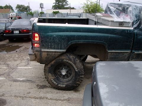 1996 Ford Bronco - Rear view of a green pickup truck with off-road tires and a toolbox in the bed.