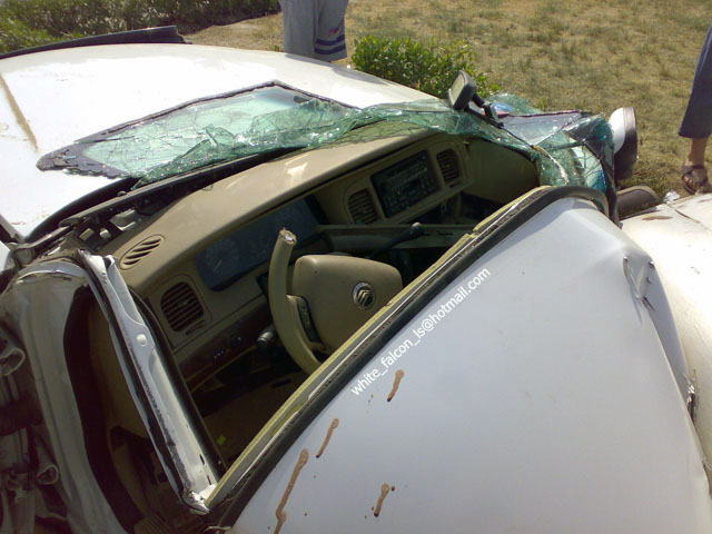 Interior of a wrecked car, windshield shattered, dashboard damaged. Looks like a 1999 Mercury Grand Marquis