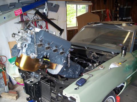 1971 Ford Ranchero - An engine is being lowered into a car with the help of an engine hoist in a garage.