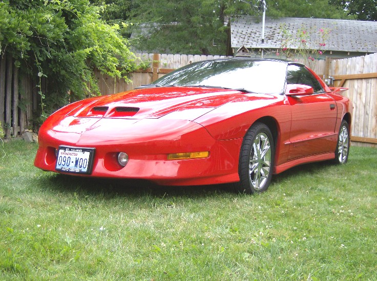 Red 1996 Pontiac Trans Am parked on grass, front 3/4 view. License plate reads 090-WOO