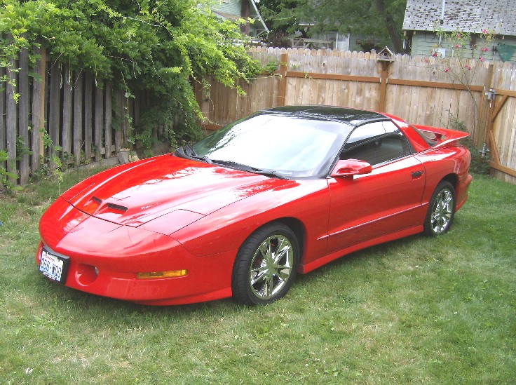 Red 1996 Pontiac Trans Am parked on grass in a backyard