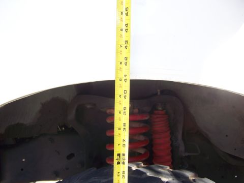 1991 Ford Bronco - A tape measure is used to gauge the height of the vehicle's suspension components.